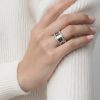 Primer plano de mano femenina luciendo un anillo acero en el dedo anular.