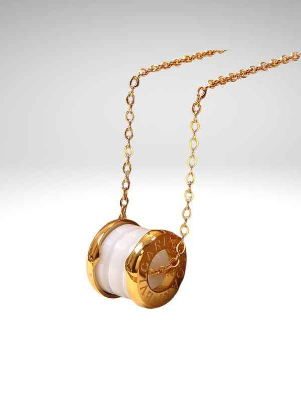 Colgante de acero 316L diseño italiano modelo cilindro cerámica blanca color dorado.