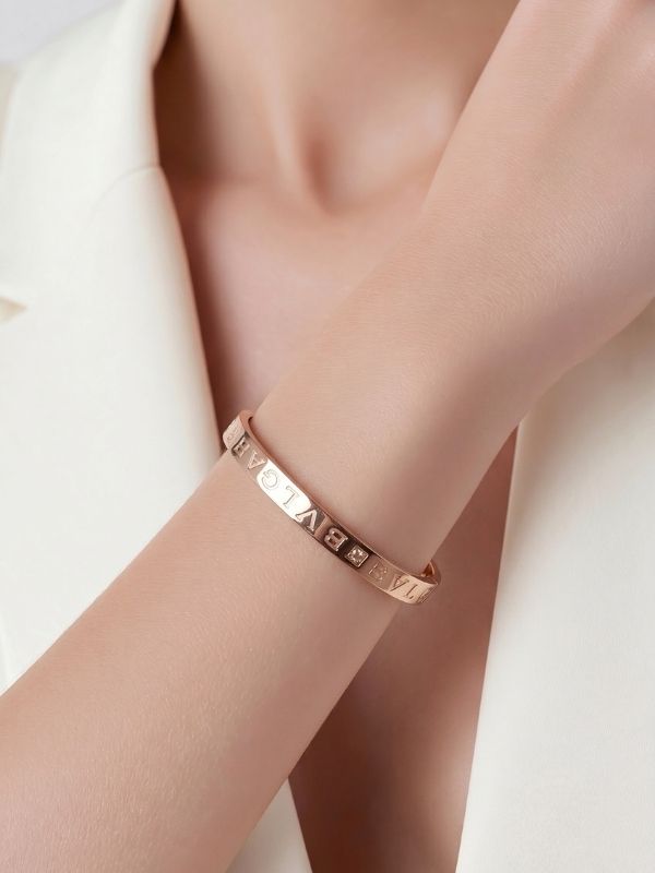 Modelo llevando pulsera rígida y articulada de acero 316L plateado.