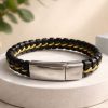 Pulsera de cuero genuino negro trenzado a mano con placa central y cierre magnético de acero inoxidable satinado.