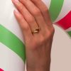 Mujer luciendo un anillo de plata de ley bañado en oro con circonita roja central clavada.
