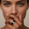 Primer plano de mano de mujer luciendo un anillo cerámica negra en el dedo anular.