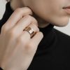 Primer plano de mano de mujer luciendo un anillo tricolor en el dedo anular.