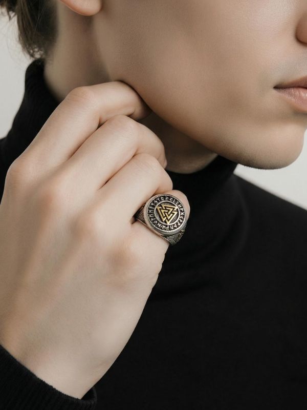 Primer plano de mano masculina luciendo un anillo acero en el dedo anular.