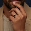 Primer plano de mano masculina luciendo un anillo acero en el dedo anular.
