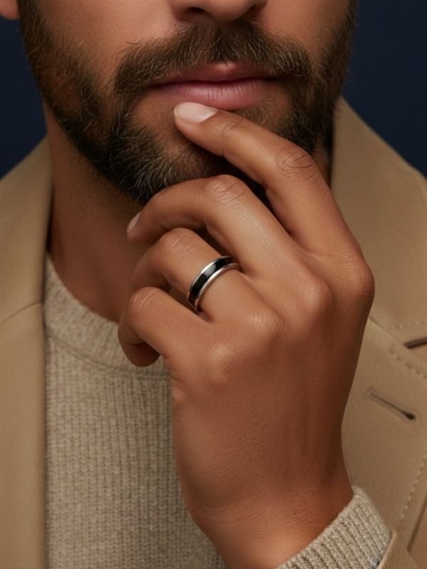 Primer plano de mano masculina luciendo un anillo acero en el dedo anular.