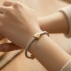 Pulsera Piel Legítima Corazón Felicidad 5 3 Mano de modelo con la pulsera de piel beige de 3mm y corazón dorado con brillantes de Roma Joyería.