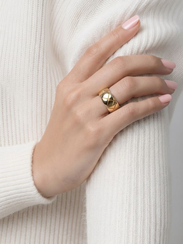 Mano de modelo luciendo el anillo ancho de rombos de acero dorado de 10mm de Estilo Chanel