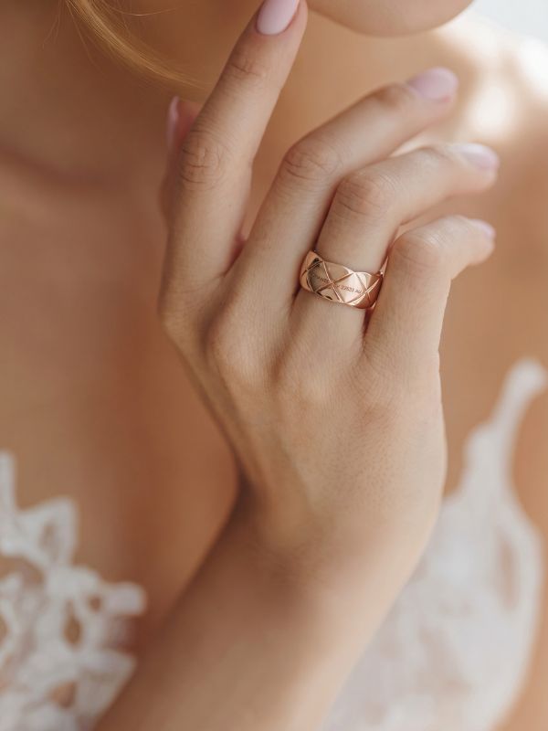 Mano de modelo luciendo el anillo ancho de rombos de acero oro rosa de 10mm de Estilo Canel.