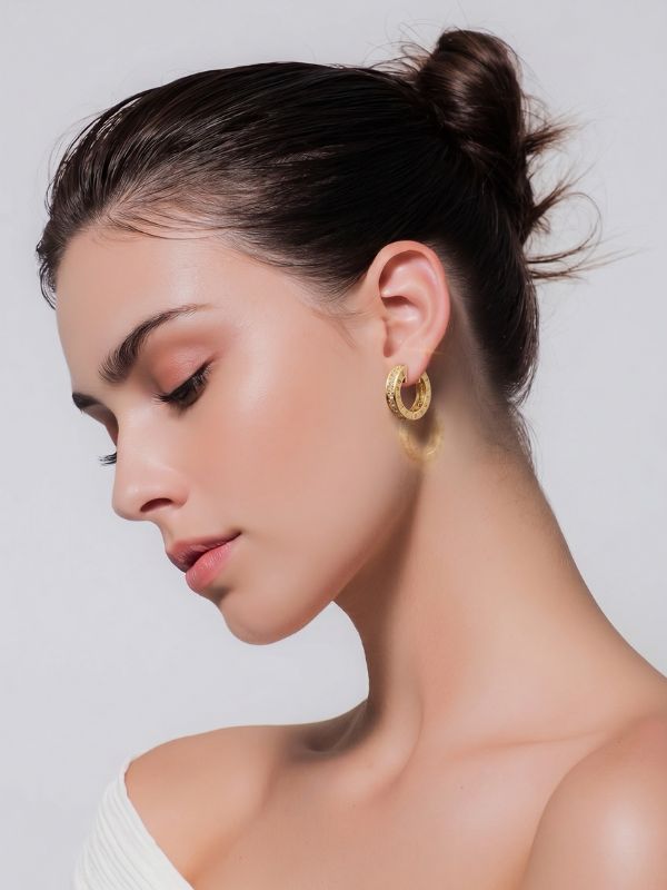 Mujer luciendo pendientes de aro abiertos con circonitas de 17mm en acero dorado diseño italiano.