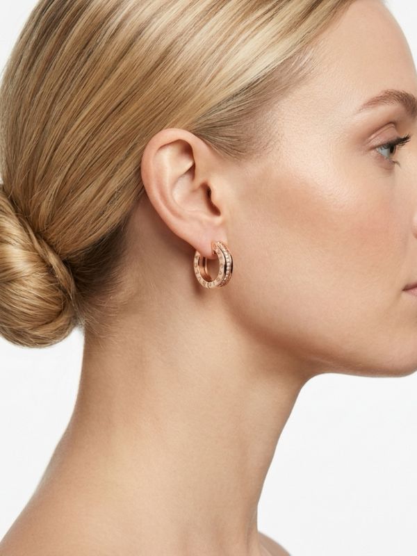 Mujer luciendo pendientes de aro abiertos con circonitas de 17mm en acero plateado diseño italiano.