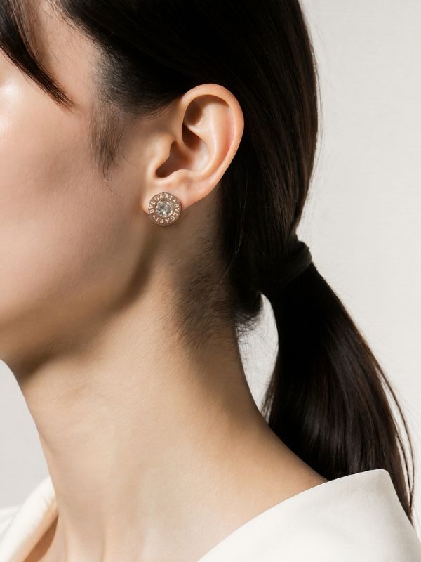 Modelo femenina luciendo pendientes italianos de acero inoxidable oro rosa de 10mm con cristal central transparente.